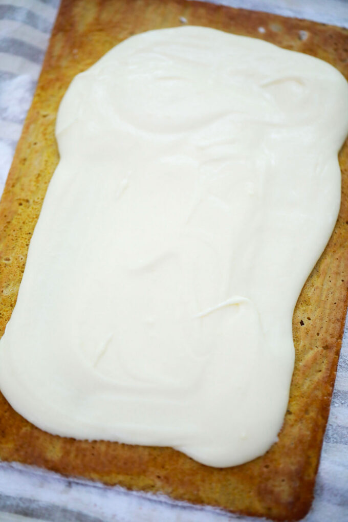 Spreading cream cheese on pumpkin cake.