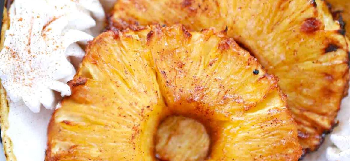 air fryer pineapple on a plate with whipped cream