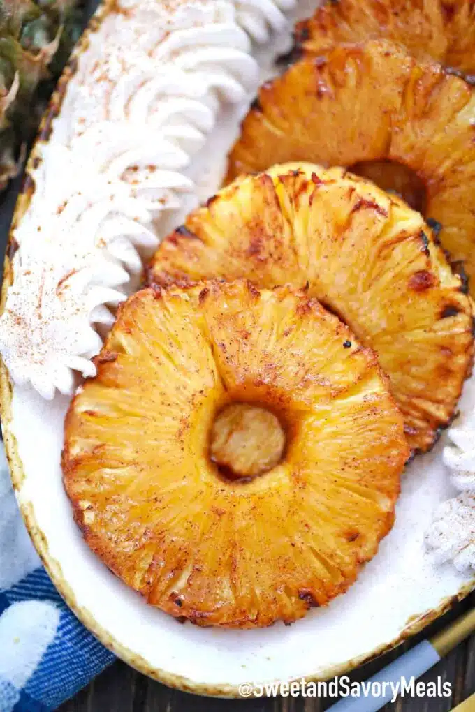 air fryer pineapple on a plate with whipped cream
