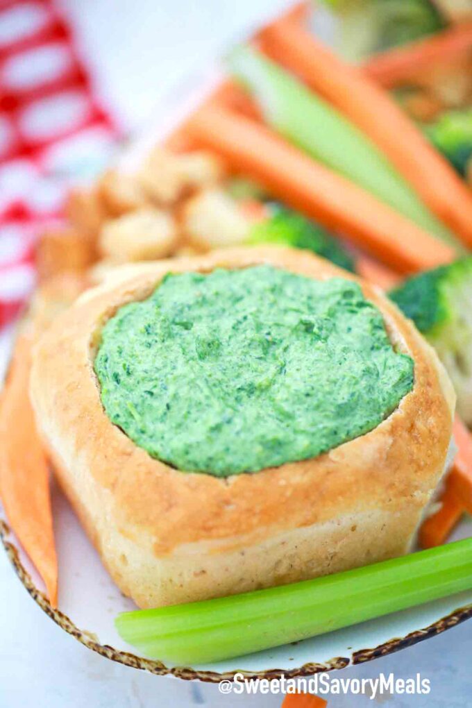 spinach dip in a bread bowl with veggies on the side