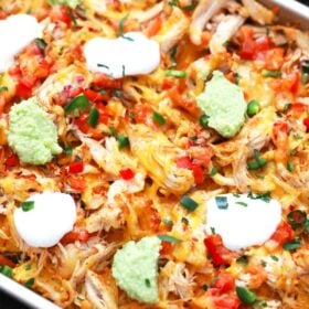 sheet pan of chicken nachos with sour cream and guacamole