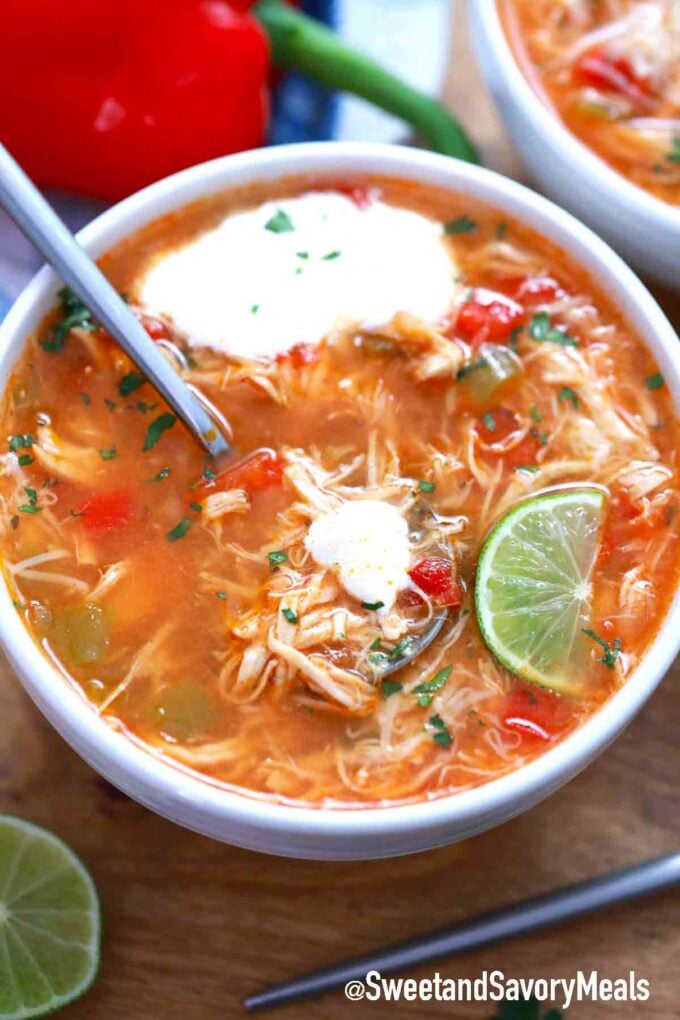 a bowl of chicken fajita soup topped with sour cream and lime