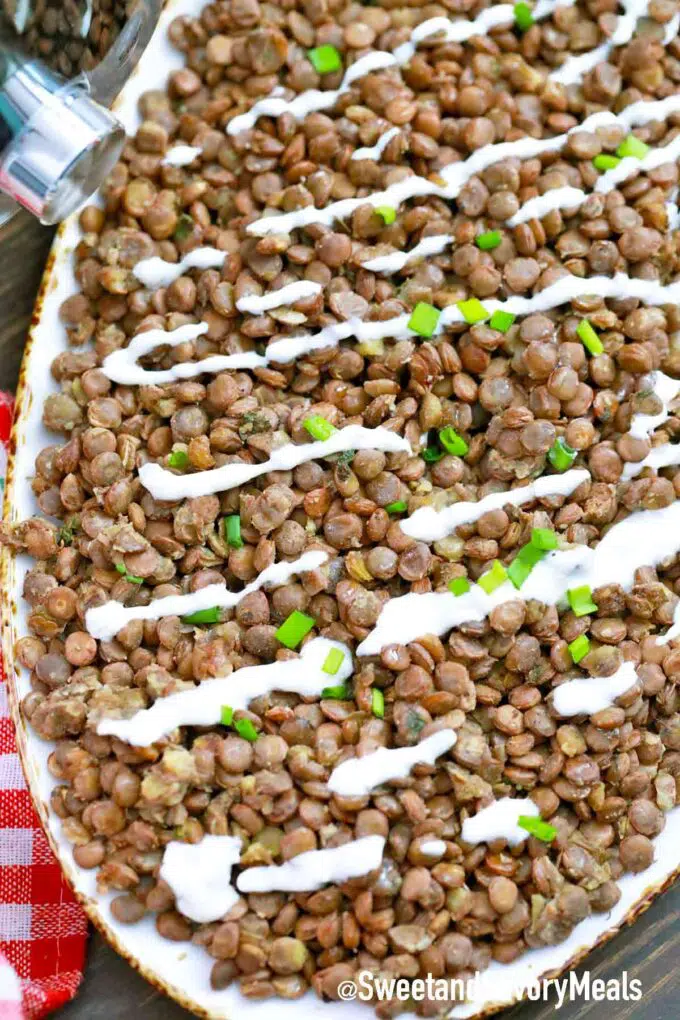 a plate of cooked lentils with white sauce