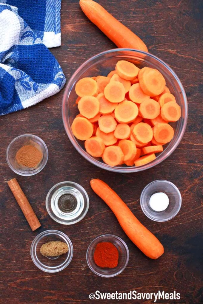 ingredients in bowls and carrots on a wooden table