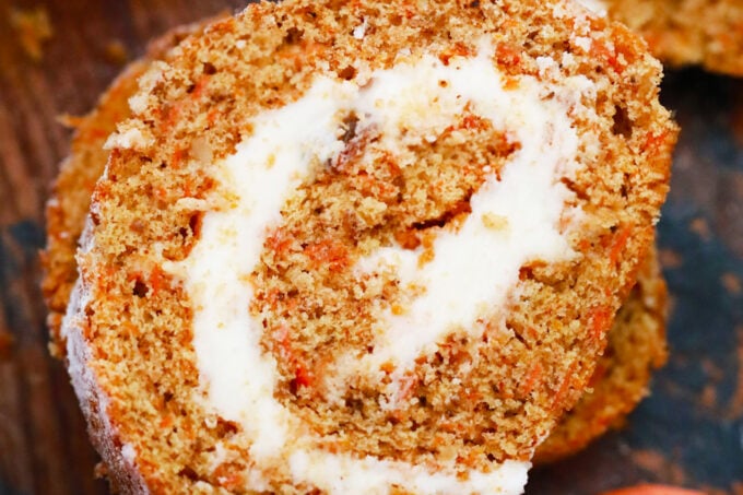 Swirled slice of carrot cake roll with cream cheese frosting.