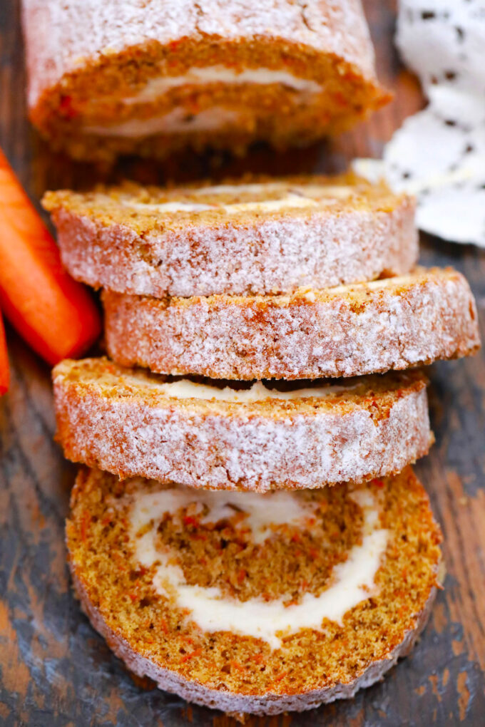 Carrot cake roll with cream cheese frosting slices topped with powdered sugar.