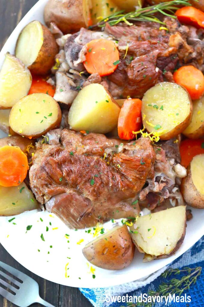 a serving plate with leg of lamb, potatoes and carrots