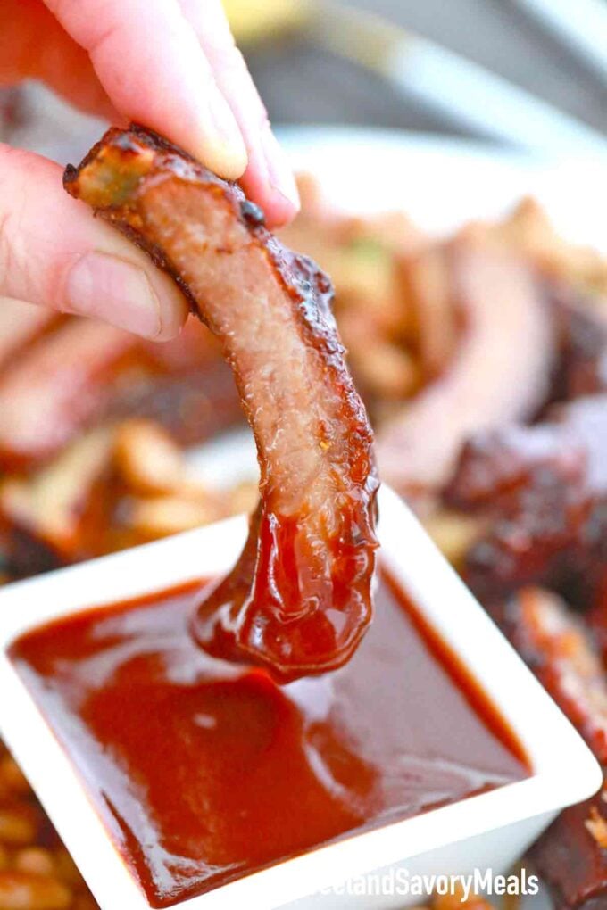 dipping a pork rib in bbq sauce