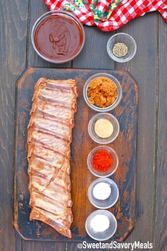rack of ribs and spices in bowls on a wooden table