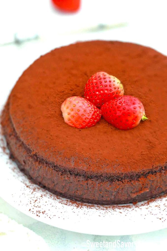 flourless chocolate cake topped with cocoa powder and strawberries