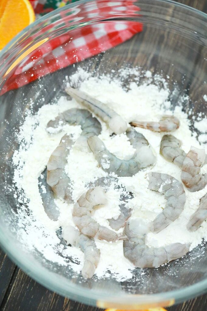 Tossing raw shrimp in a bowl with cornstrach.