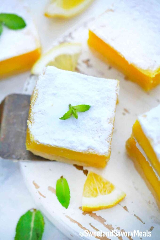 lemon square covered with powdered sugar on a white cutting board