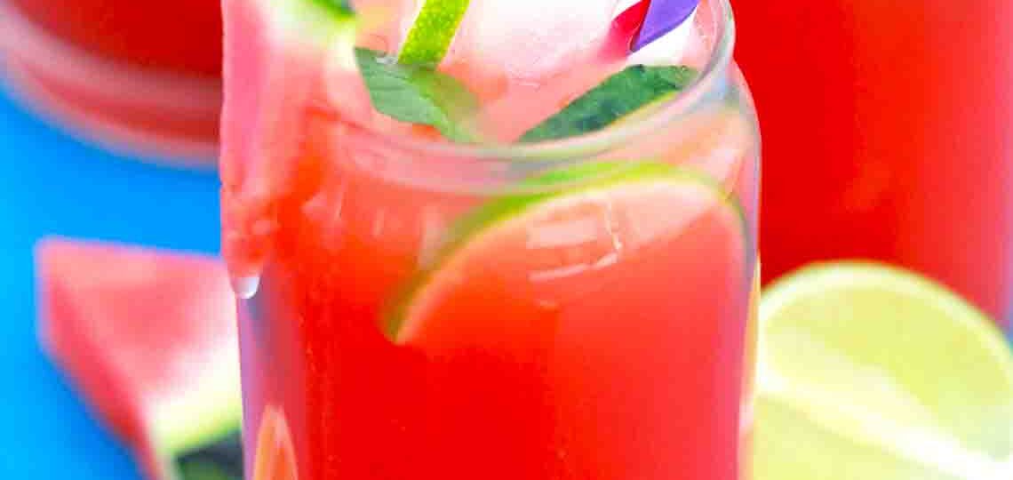 a glass of watermelon lemonade with lime slices