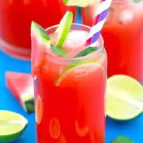 a glass of watermelon lemonade with lime slices