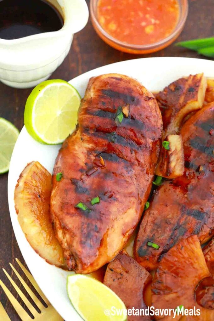 a plate of grilled chicken with lime wedges on the side