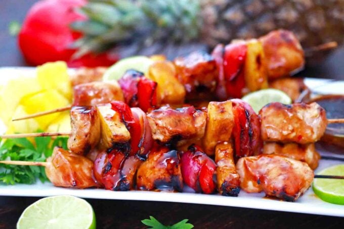 BBQ chicken kabobs arranged on a plate with a fresh pineapple in the background