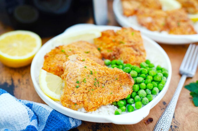 Air fryer crispy fish fillets served with rice and green peas.