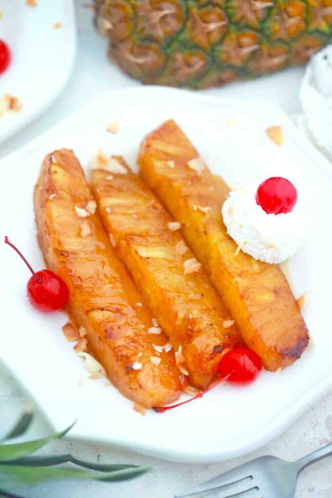 fried pineapple served with whipped cream and maraschino cherries