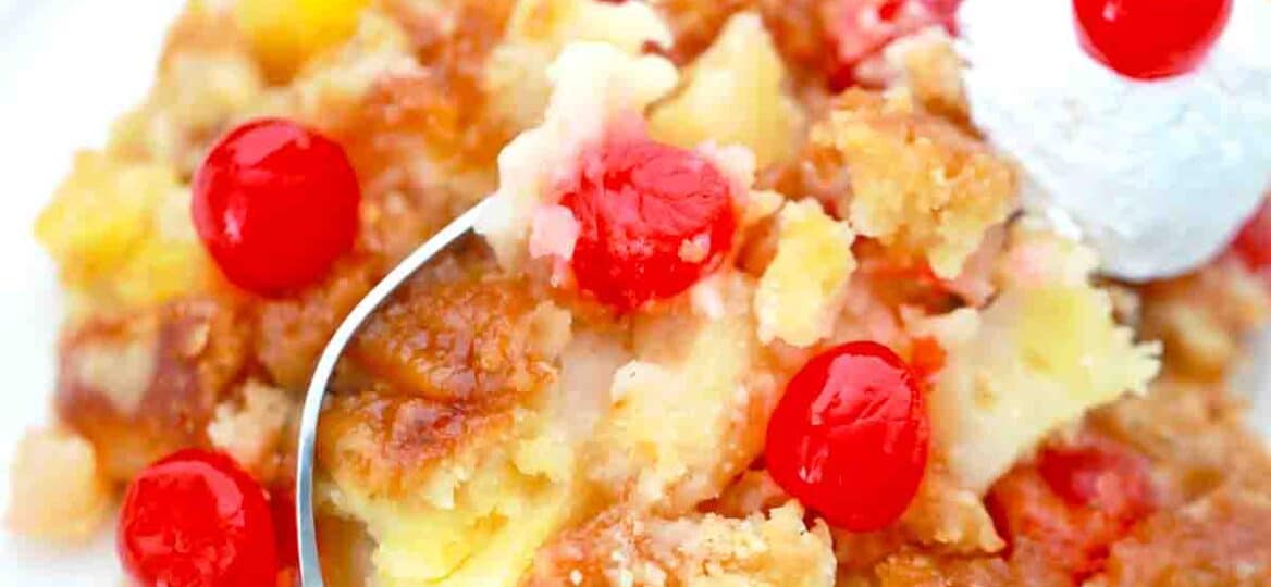an overhead shot of a plate with pineapple dump cake with maraschino cherries