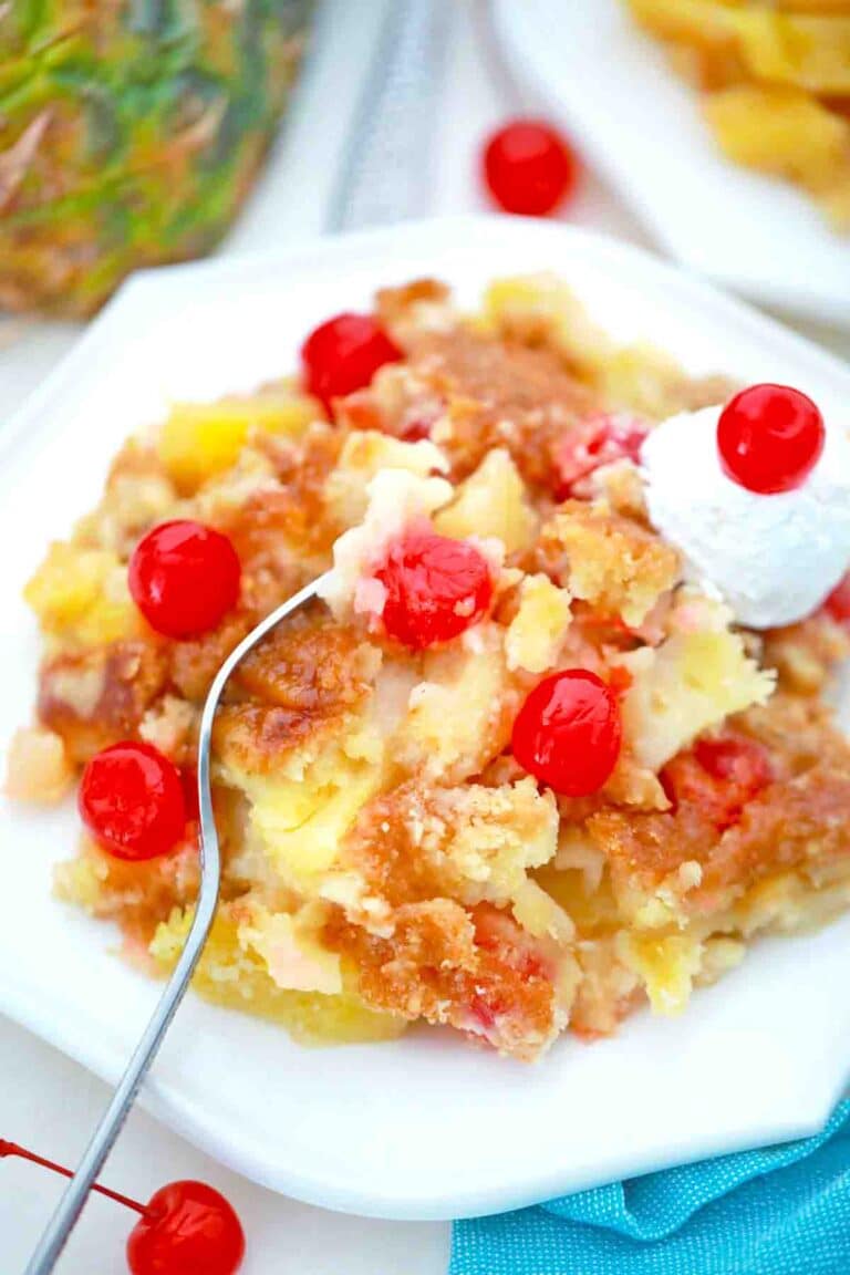 an overhead shot of a plate with pineapple dump cake with maraschino cherries