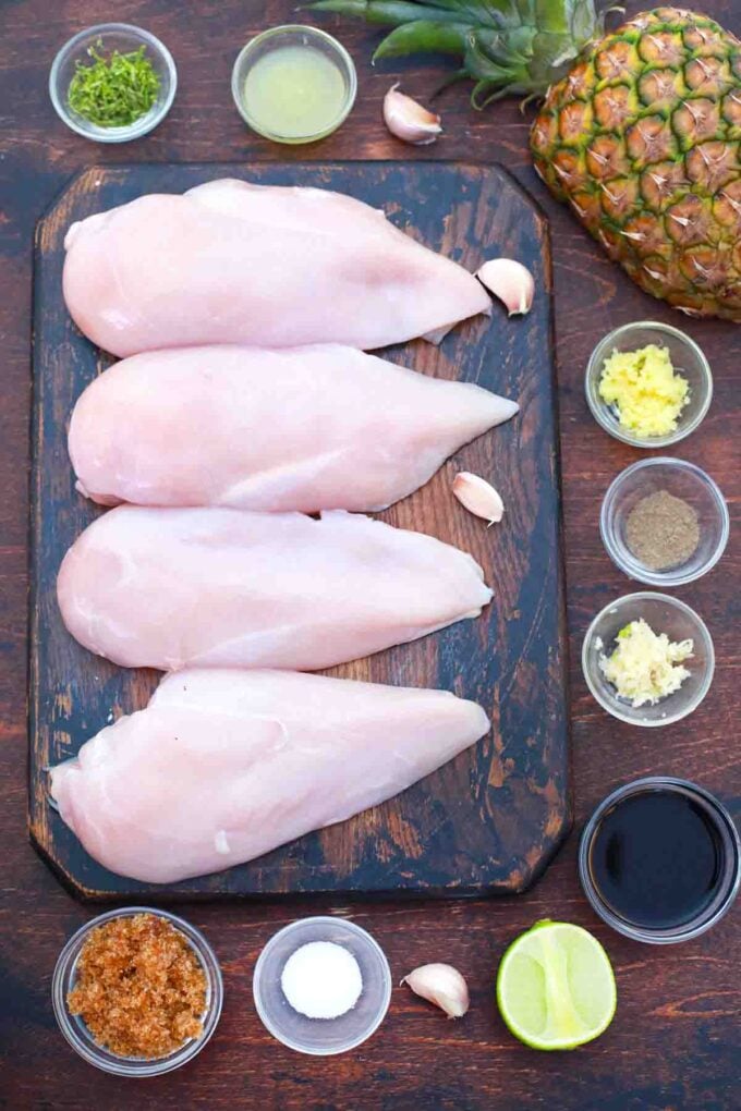 chicken breasts on a cutting board and ingredients in bowls