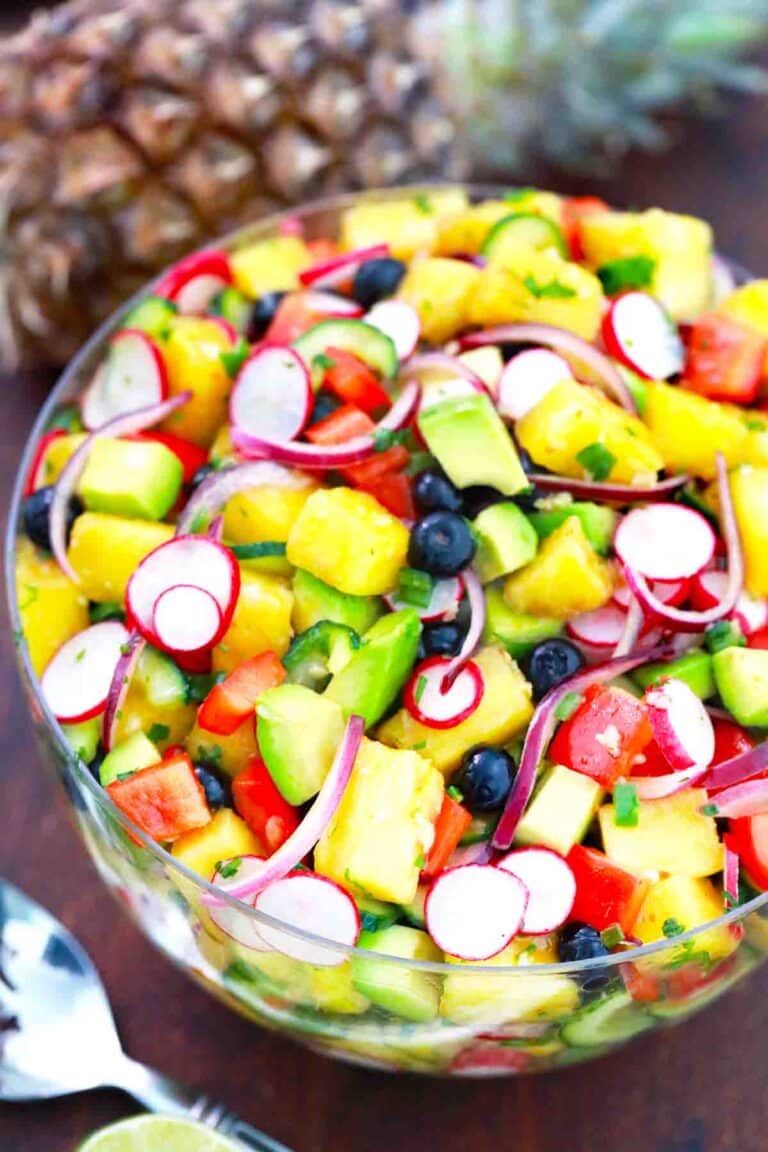 large bowl of pineapple cucumber salad and a pineapple in the background