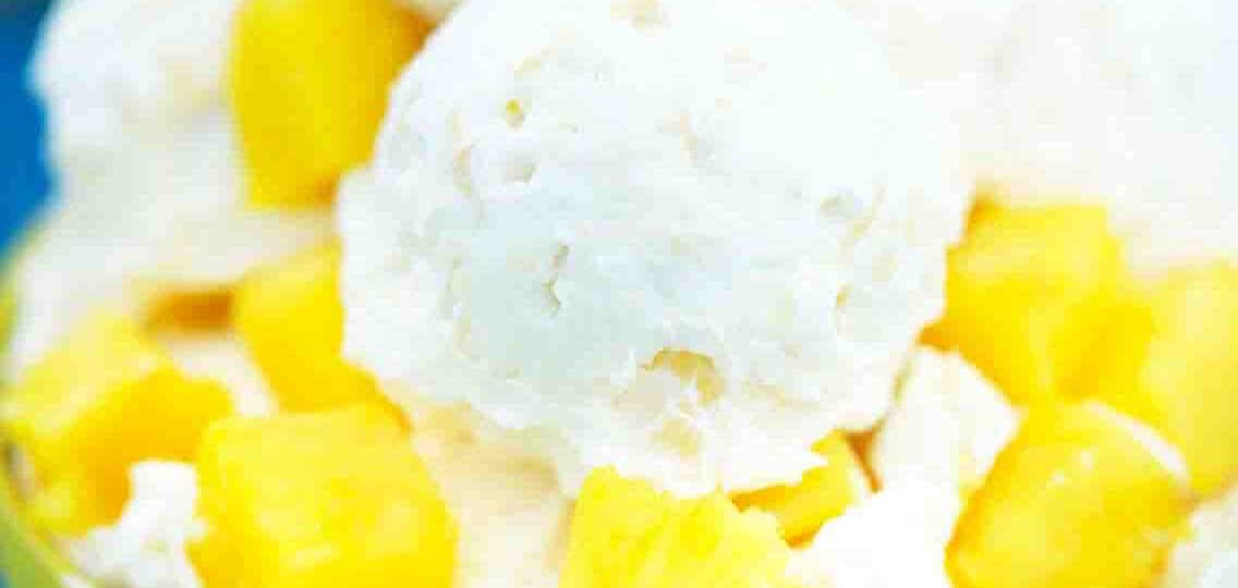 a close up photo of a bowl of pineapple ice cream with fresh pineapple