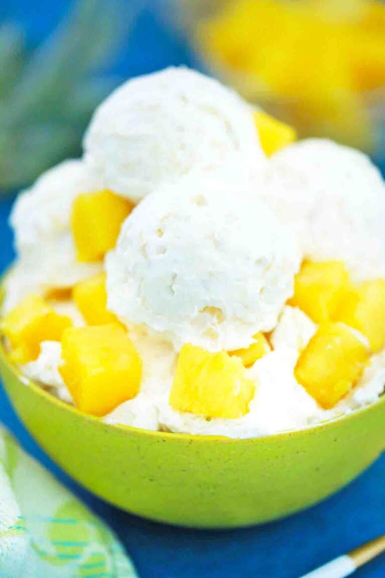 a close up photo of a bowl of pineapple ice cream with fresh pineapple