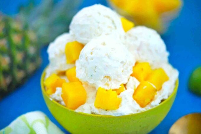 a horizontal photo of a bowl of pineapple ice cream with fresh pineapple