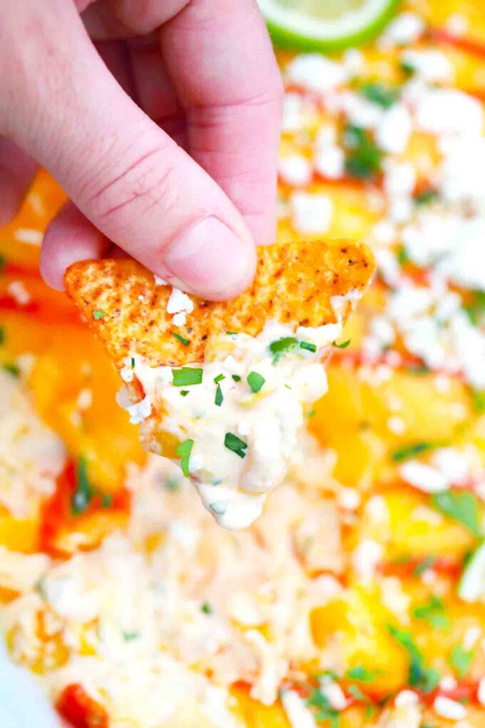 close shot of holding a corn chip dipped into mexican street corn dip