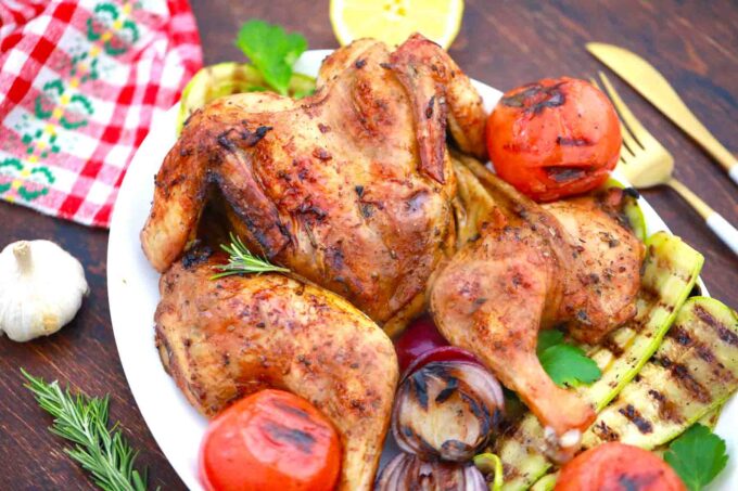 a platter with grilled whole chicken and veggies
