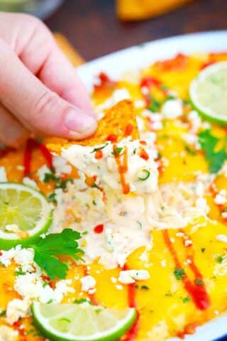 overhead shot of dipping corn chip in melty mexican street corn dip