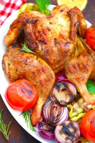 close shop of crispy grilled whole chicken and grilled vegetables