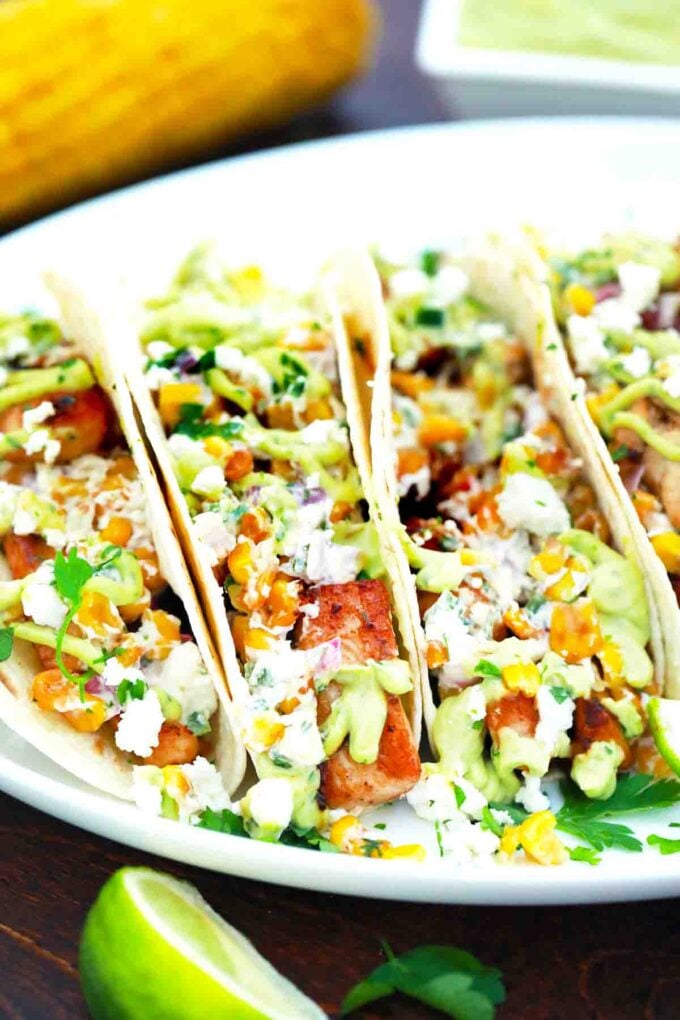 a platter of loaded mexican street corn chicken tacos with corn in background