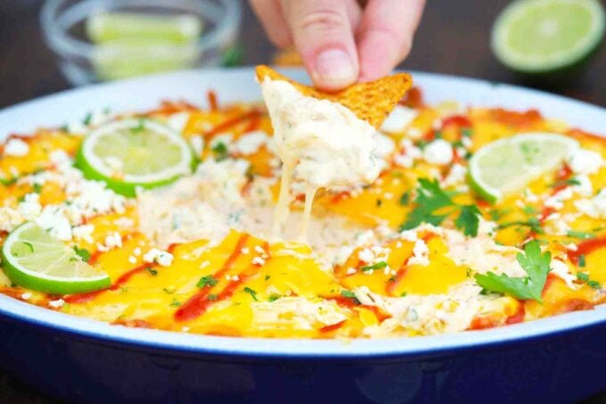 dipping corn chip into a platter of mexican street corn dip
