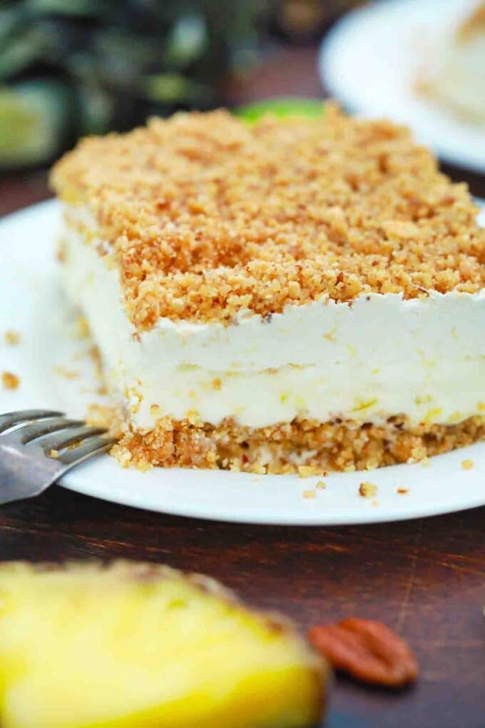 a slice of no bake pineapple dream dessert with a pineapple in the background