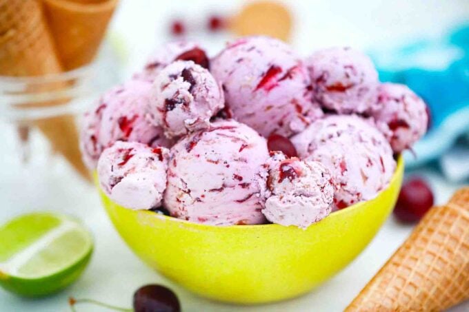 a bowl full of no churn cherry ice cream with a lime on the side