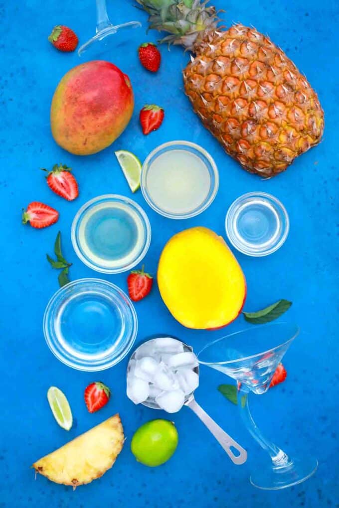 overhead shot of mango pineapple water lemon juice on a blue board