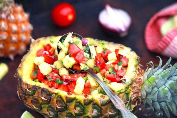 pineapple salsa with a spoon in a fresh pineapple