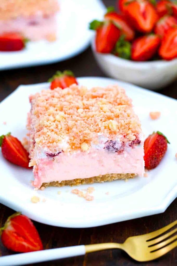 a slice of strawberry lasagna dream dessert with fresh strawberries in the background