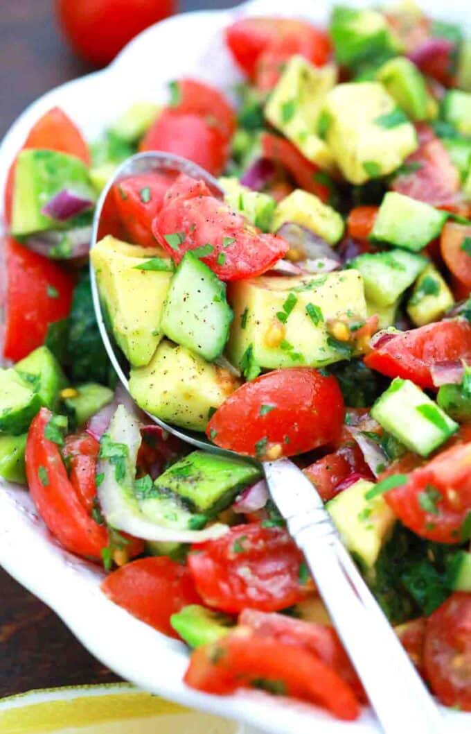 a close shot of a spoonful of vegan cucumber tomato avocado salad