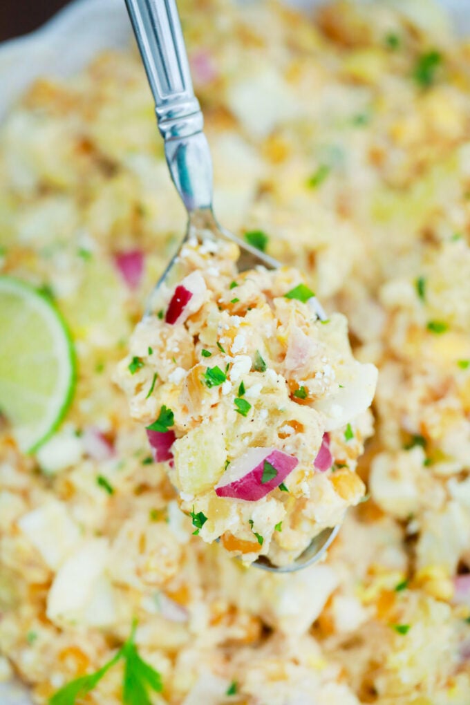 A spoonful of Mexican street corn potato salad with red onions and lime.