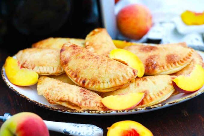 a plate of air fryer peach hand pies with sliced peaches