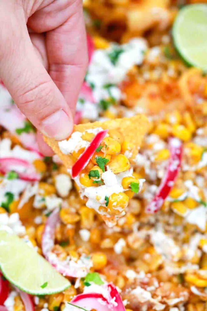 scooping mexican street corn nachos on corn chips