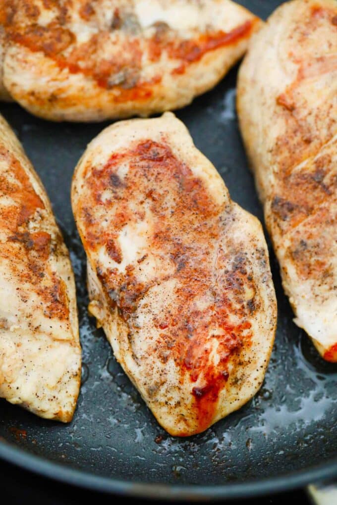 Browning four chicken breasts in a skillet.
