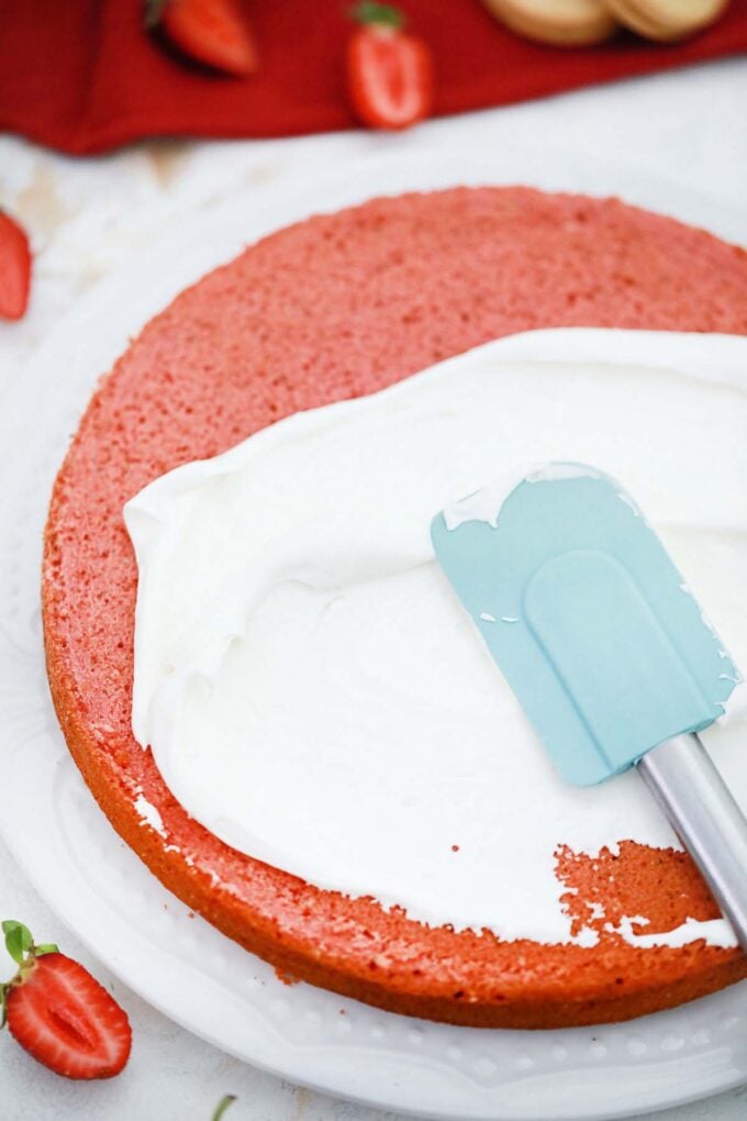 Frosting a strawberry cake layer.