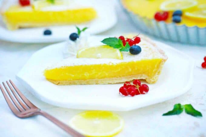 a slice of lemon tart with another slice in the background
