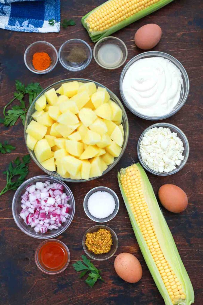 overhead shot of potatoes corn onion mayo spices cheese in bowls on a table