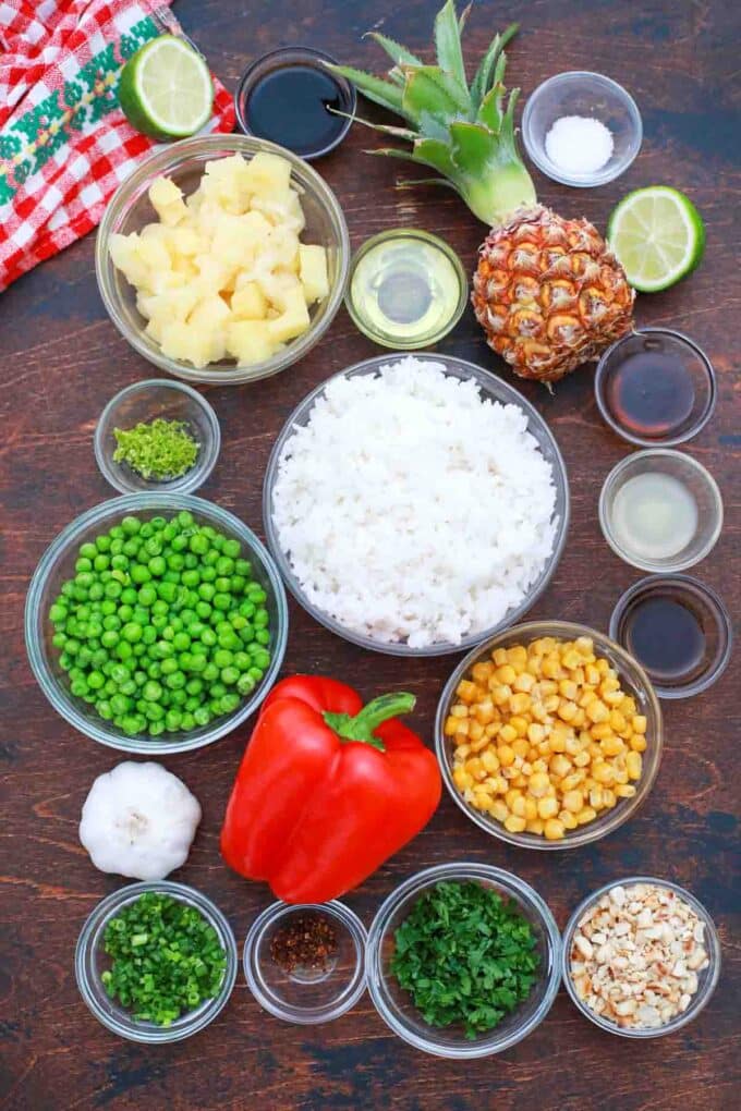 overhead shot of rice pineapple veggies and sauces in bowls on a table