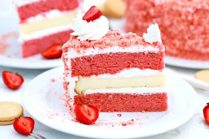strawberry crunch cheesecake cake slice on a plate with the cake in the background